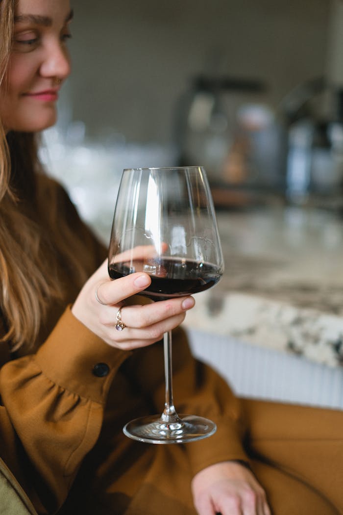Woman in brown dress holds a glass of red wine at a sophisticated bar. Perfect for lifestyle and leisure themes.
