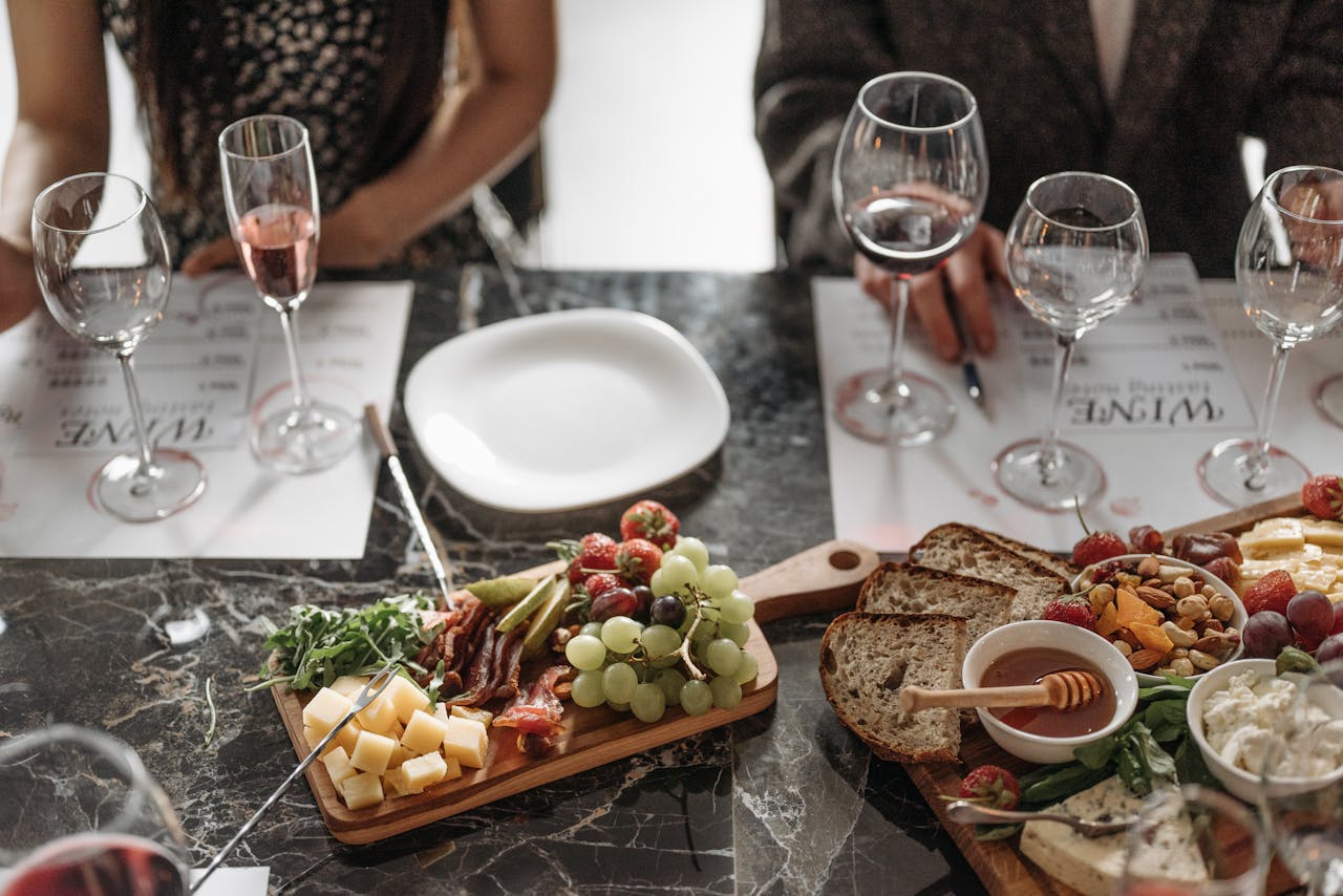 An elegant dining setup featuring glasses of wine and a cheese platter on a marble table.
